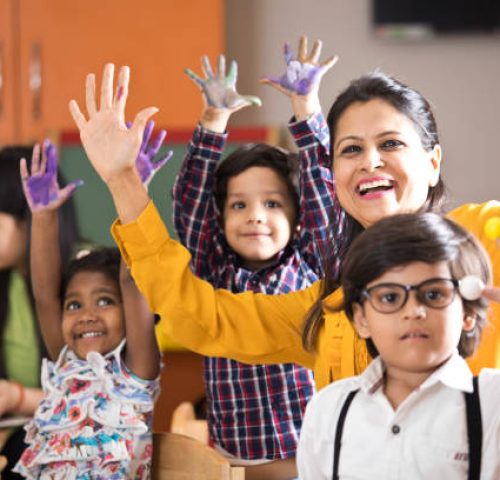 Teacher with preschool students having fun while finger painting at class Teacher with preschool students having fun while finger painting at class
