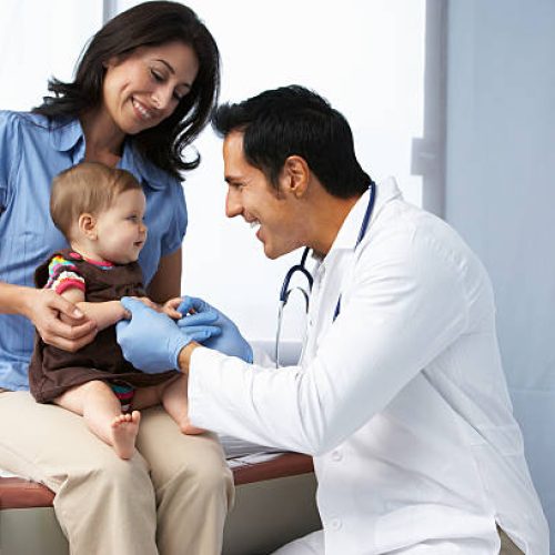 Doctor In Surgery Examining Baby Girl With Mother Smiling. Doctor In Surgery Examining Baby Girl With Mother Smiling.